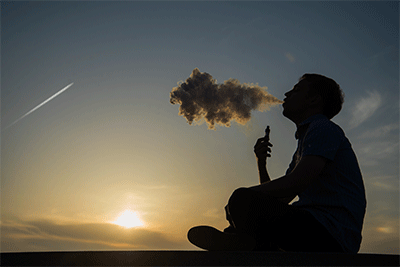 Man Vaping Large Clouds With a Summer Sunset