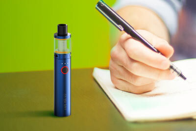 SMOK Vape Pen V2 on a Desk Next to Man Writing