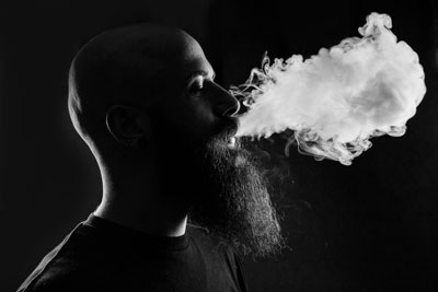 Vaper exhaling a cloud of vapour with e cigarette