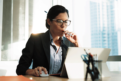 Woman Vaping Indoors While Using the Laptop